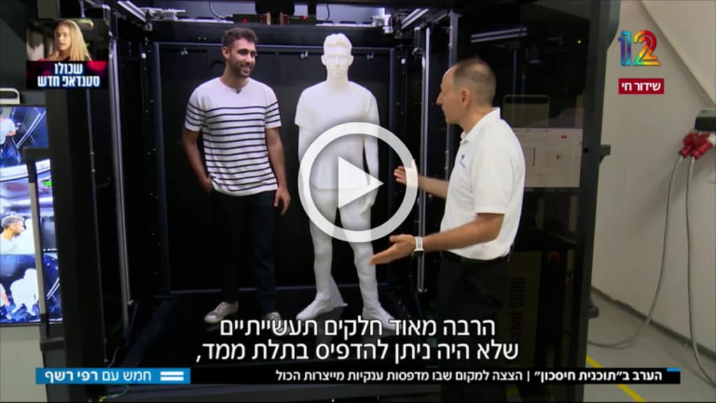 A screenshot of a 3D printed figure, life-size, with a person whom it's modeled after, with the CEO, Erez Zimmerman standing in front of the printer 