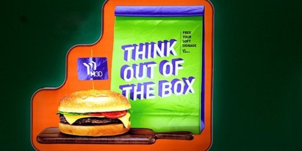 Image of a 3d advertising desin of a hamburger and a take-away bag that reads "Think Out Of The Box"